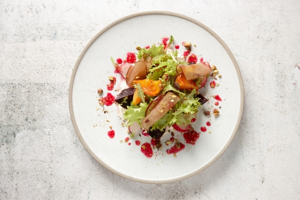Plate of fresh salad of lettuce, beetroot, radish, stone fruit and vinaigrette - from above - Australian Stock Image