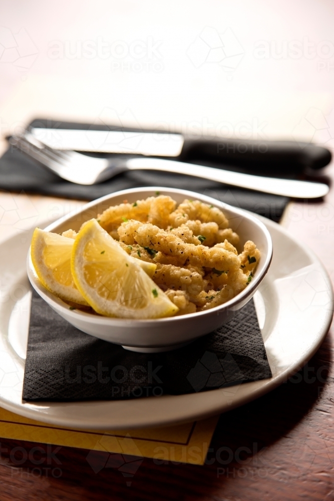 Plate of fried squid and lemon slices - Australian Stock Image