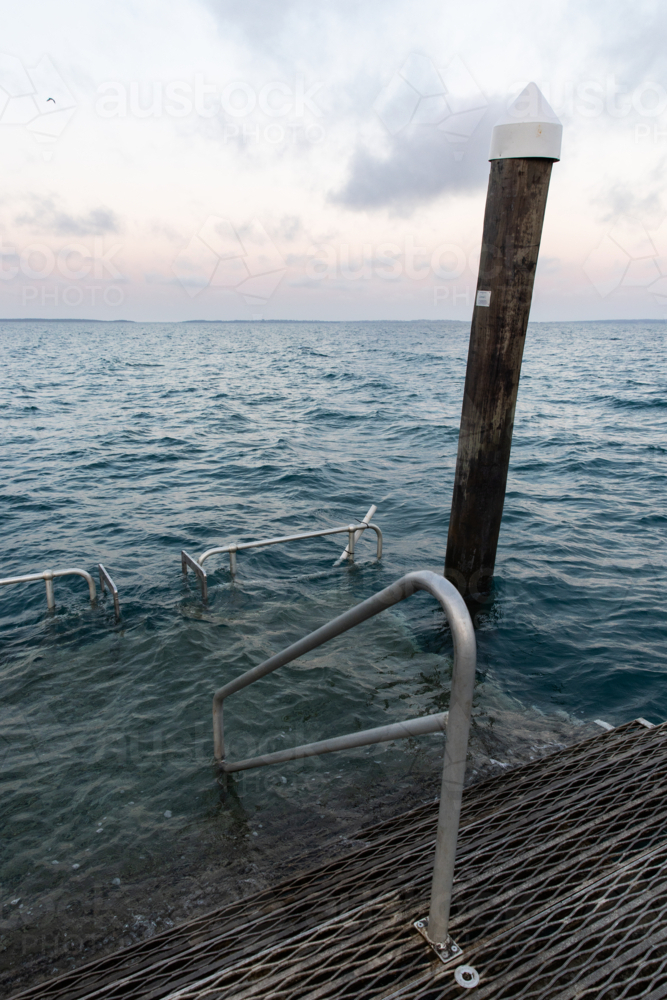 platform at the end of a jetty under water at high tide before dawn - Australian Stock Image