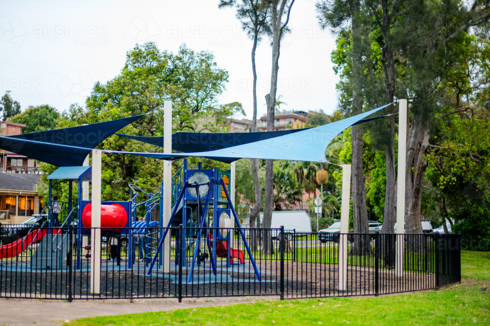 playground equipment in a vibrant park, on a sunny day under shade. - Australian Stock Image