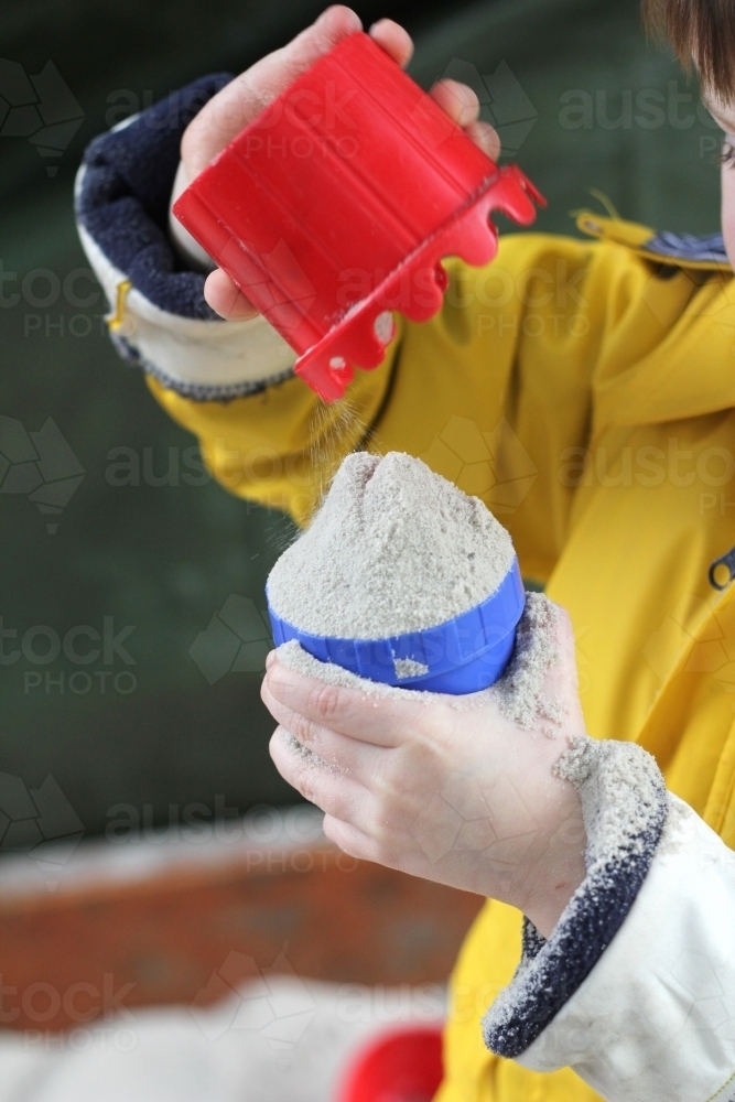 Playing with cups in the sandpit - Australian Stock Image