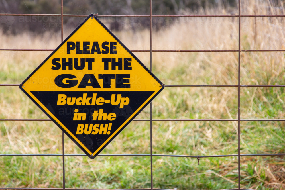 Please shut the gate, buckle-up in the bush sign on Australian country gate - Australian Stock Image