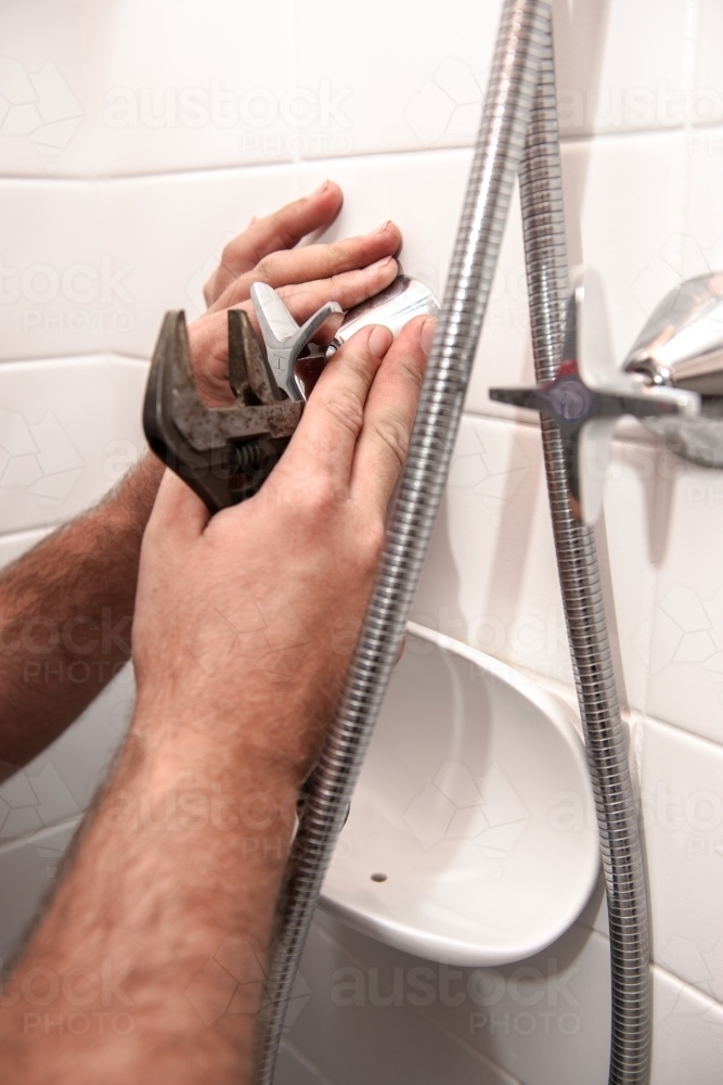 Plumber installing a shower head and tap - Australian Stock Image