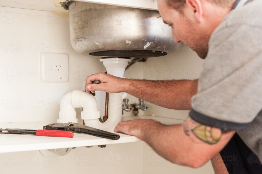 Plumber installing a sink and pipes - Australian Stock Image