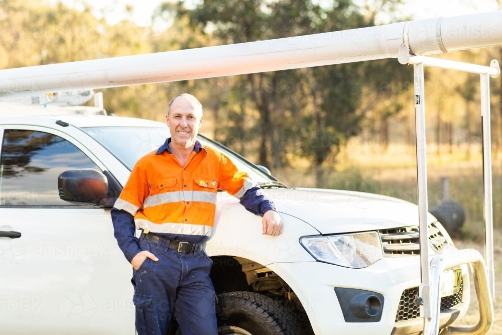 Plumber tradie leaning on work vehicle - Australian Stock Image