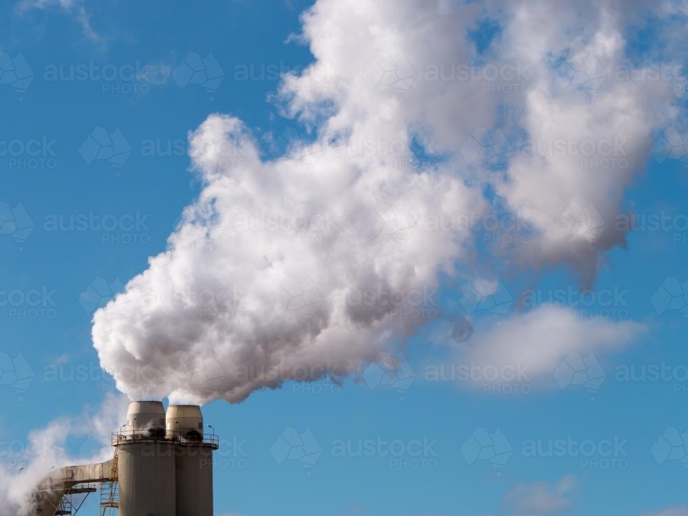 Image of Plumes of steam rising from industrial chimneys into a blue ...