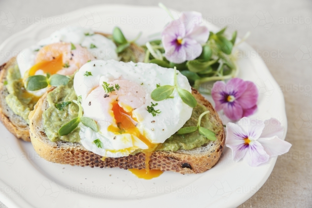 Poached eggs with avocado and sunflower sprout on sourdough toasts - Australian Stock Image