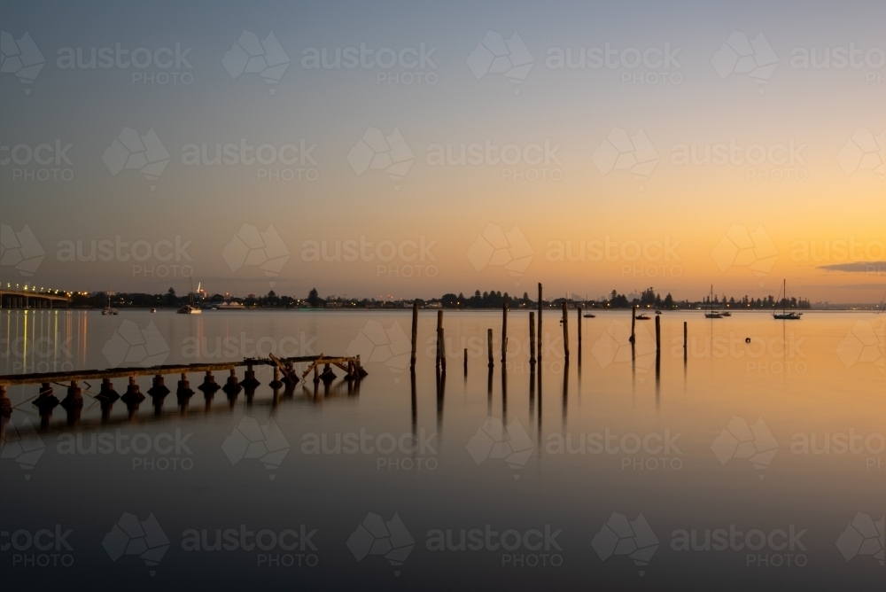 Poles of an old heritage wharf with reflections taken at blue hour / golden hour - Australian Stock Image
