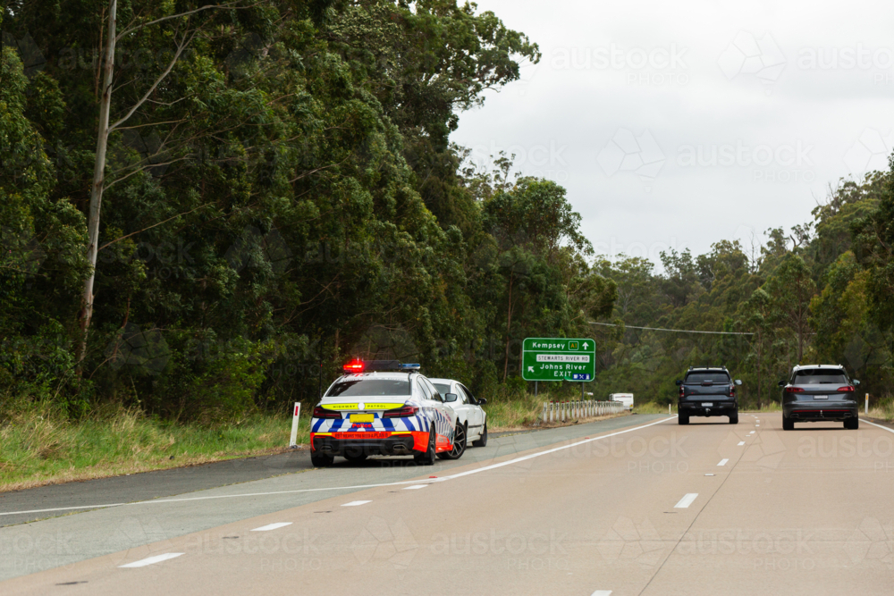 Police car pulled over behind car beside pacific highway road on the east coast of Australia - Australian Stock Image