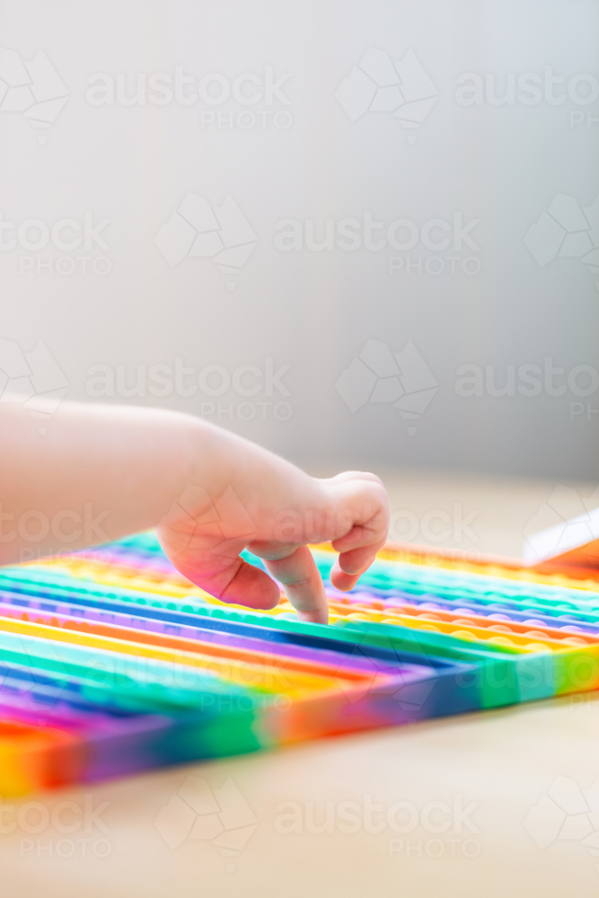 Poppet pop fidget toy being pressed by childs finger with copy space - Australian Stock Image