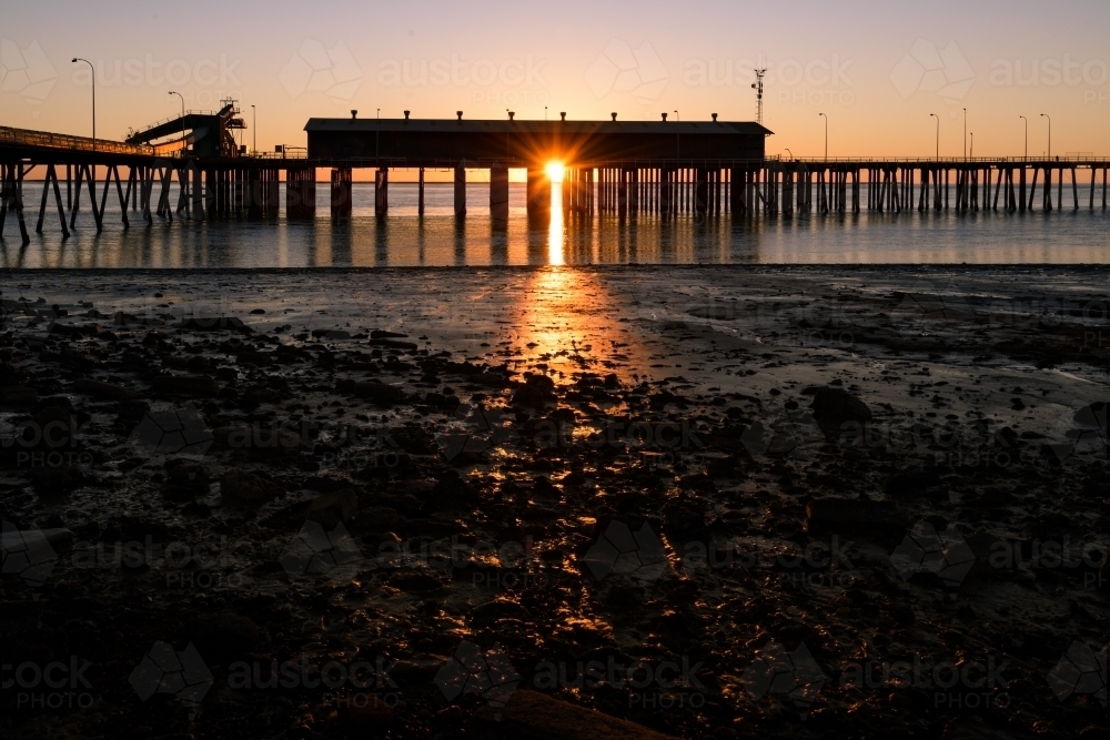 Port Jetty at low tide with sunburst and sunset colours - Australian Stock Image