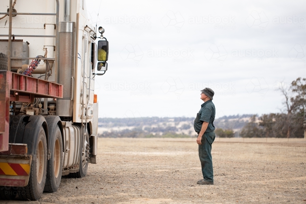 portly fellow looking up to talk to a truck driver - Australian Stock Image