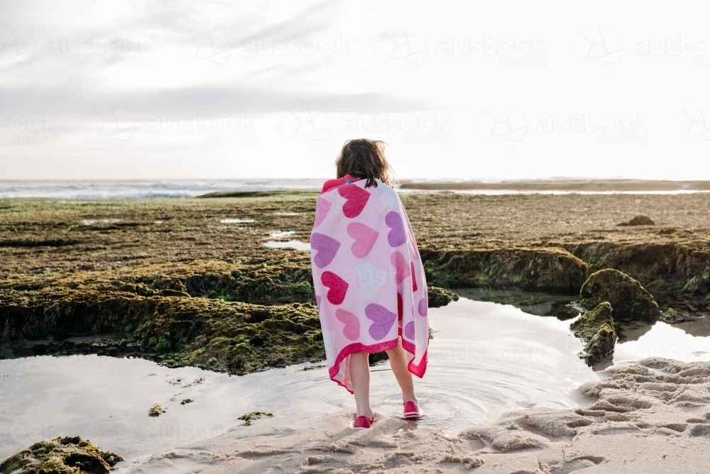 Portrait from behind of young girl wrapped in a beach towel, Victoria, Australia - Australian Stock Image
