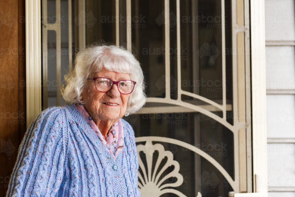 Portrait of 99 year old elderly Australian woman standing by front door of her home - Australian Stock Image