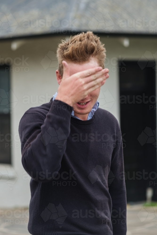 portrait of a 20 year old man, hiding behind his hand - Australian Stock Image