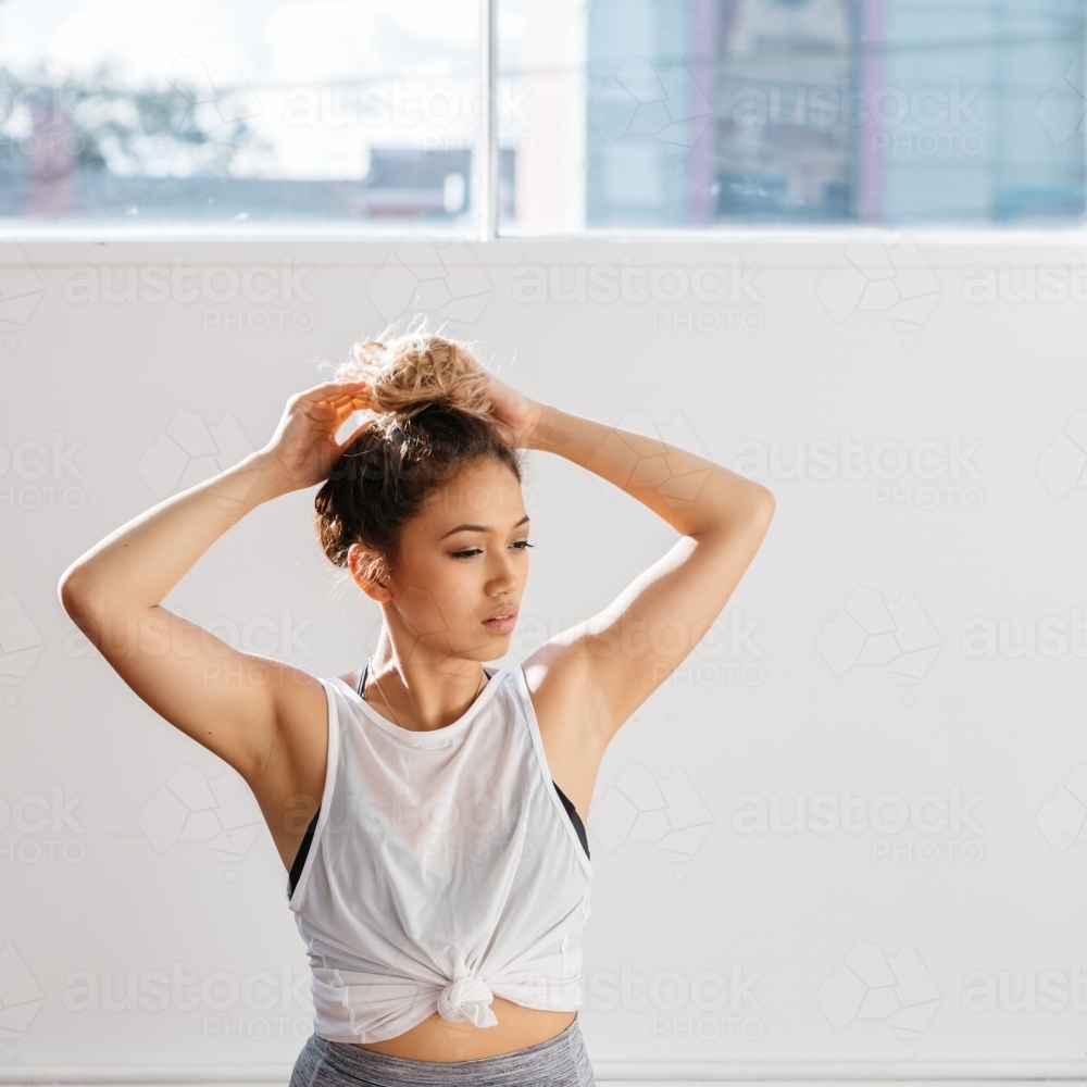 Portrait of a beautiful girl putting hair up in a dance studio - Australian Stock Image
