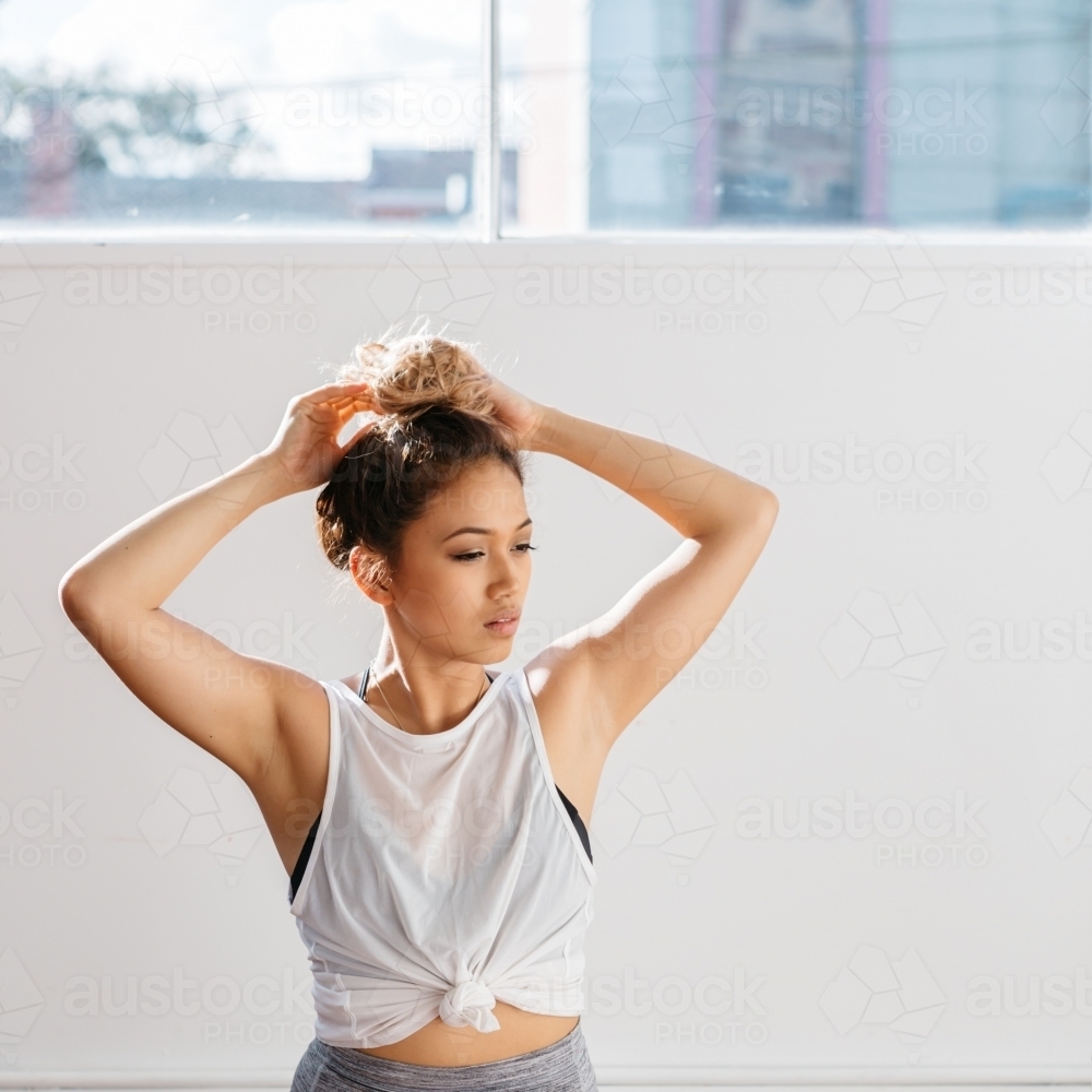 Portrait of a beautiful girl putting hair up in a dance studio - Australian Stock Image