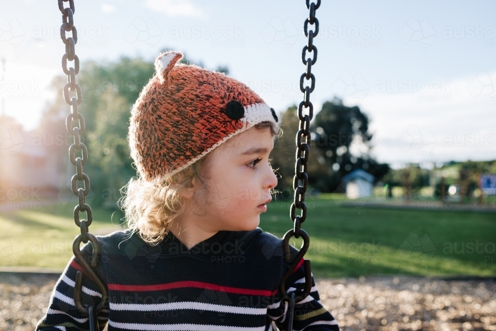 Portrait of a child on a swing in the park in the afternoon - Australian Stock Image