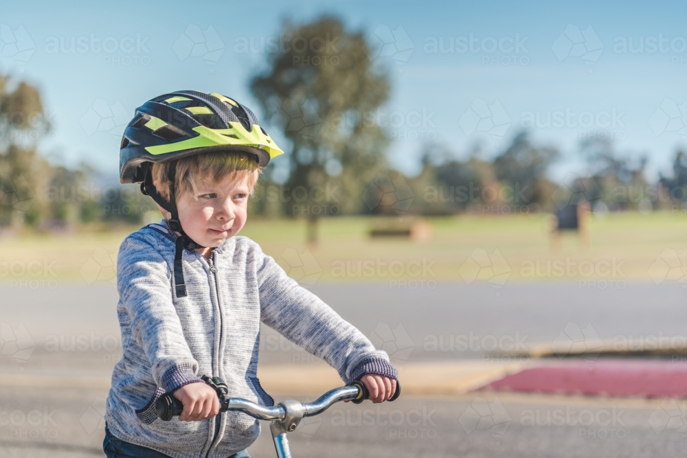 Portrait of a child wearing a helmet while riding his balance bike on track in Adelaide Parklands - Australian Stock Image