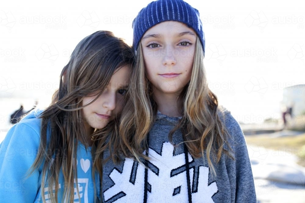 Portrait of a girl leaning on another girl's shoulder outside - Australian Stock Image