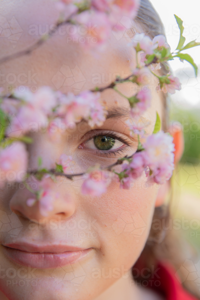 Portrait of a girl looking through spring blossoms - Australian Stock Image