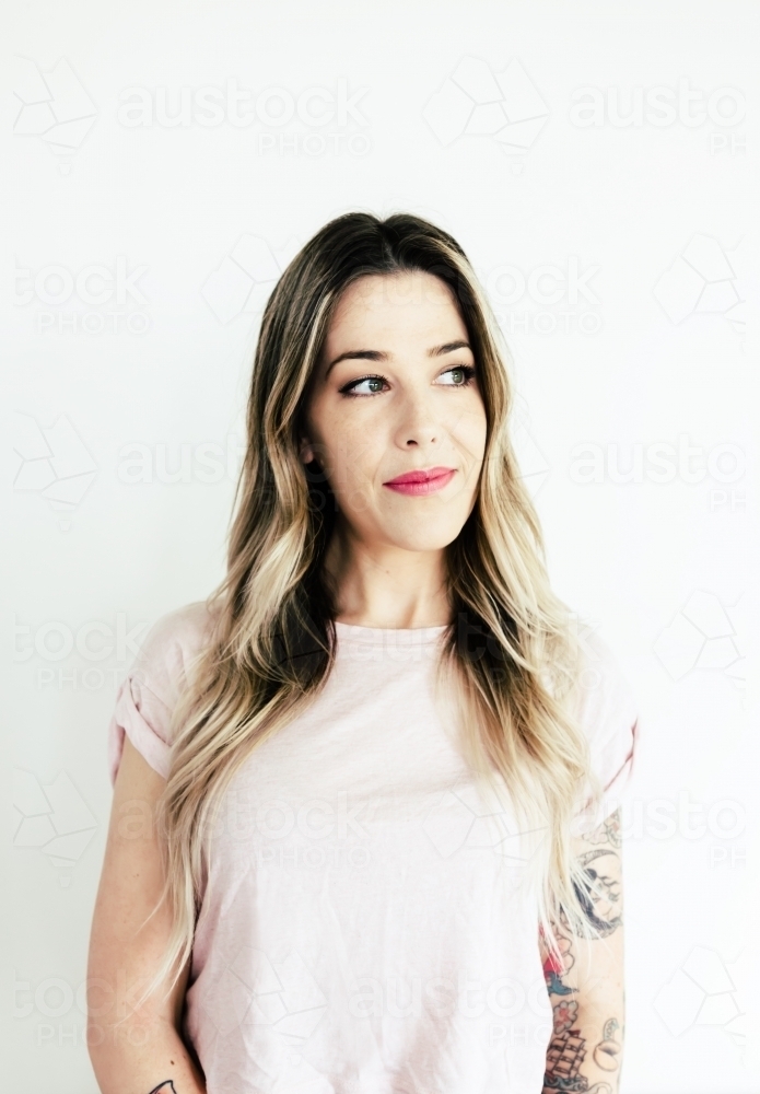 Portrait of a girl with arm tattoos looking sideways - Australian Stock Image