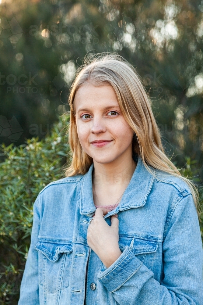 Portrait of a happy blonde girl in denim jacket outside - Australian Stock Image