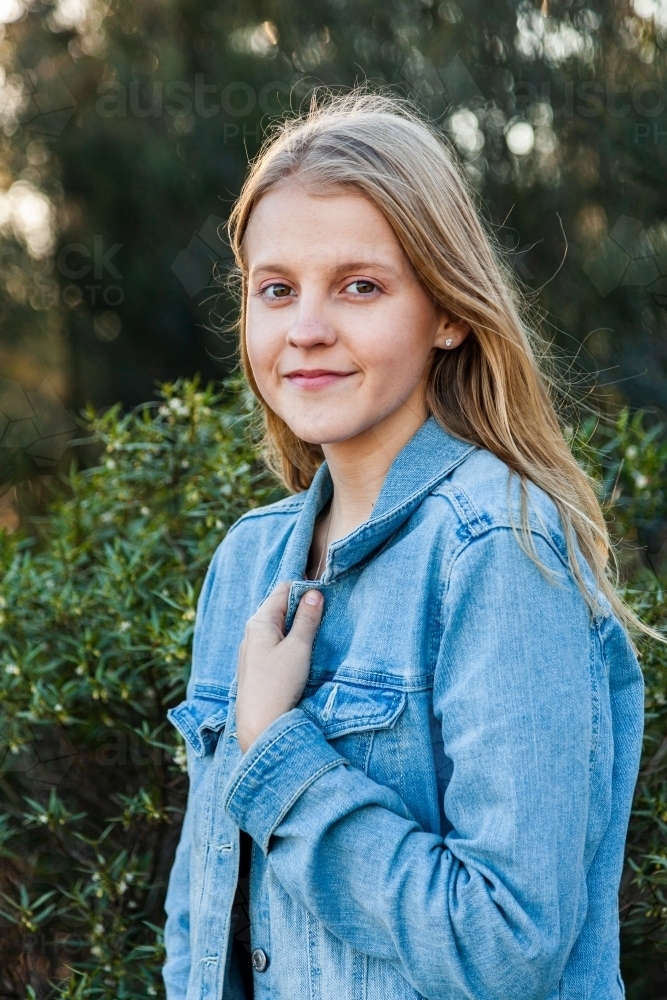 Portrait of a happy blonde girl in denim jacket outside - Australian Stock Image