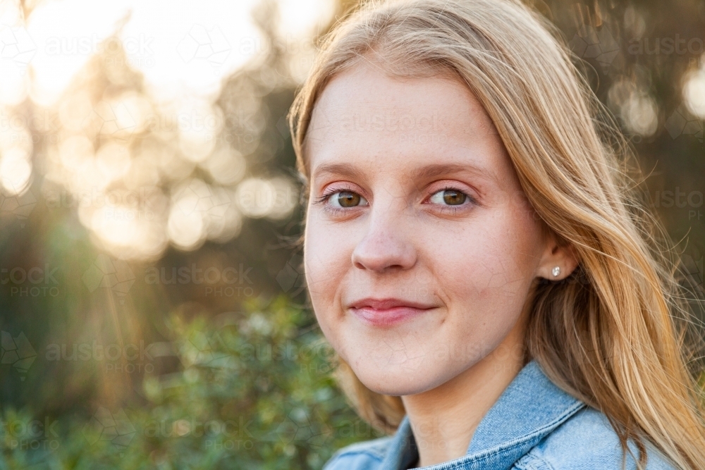 Portrait of a happy blonde girl in denim jacket outside - Australian Stock Image