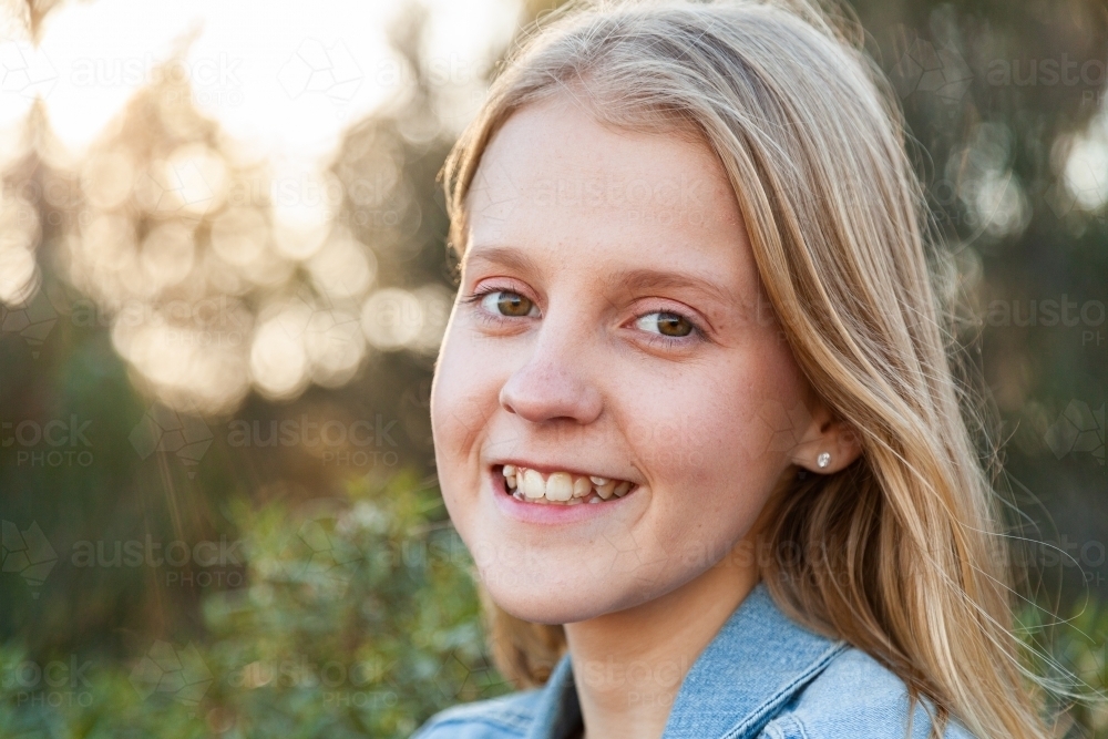 Portrait of a happy blonde girl in denim jacket outside - Australian Stock Image