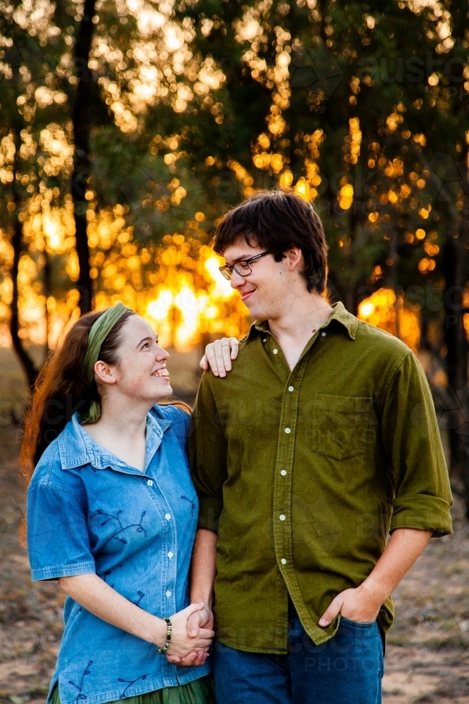 Portrait of a happy couple smiling at sunset with golden bokeh light - Australian Stock Image