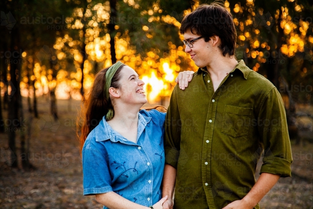 Portrait of a happy couple smiling at sunset with golden bokeh light - Australian Stock Image