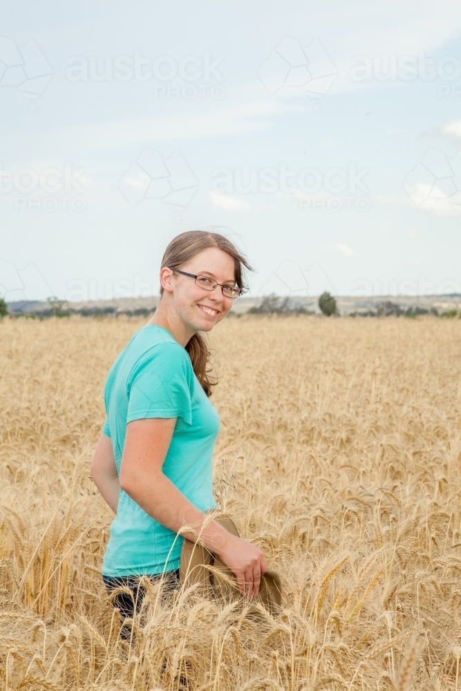 Portrait of a happy kid in paddock of bearded wheat crop on a farm - Australian Stock Image