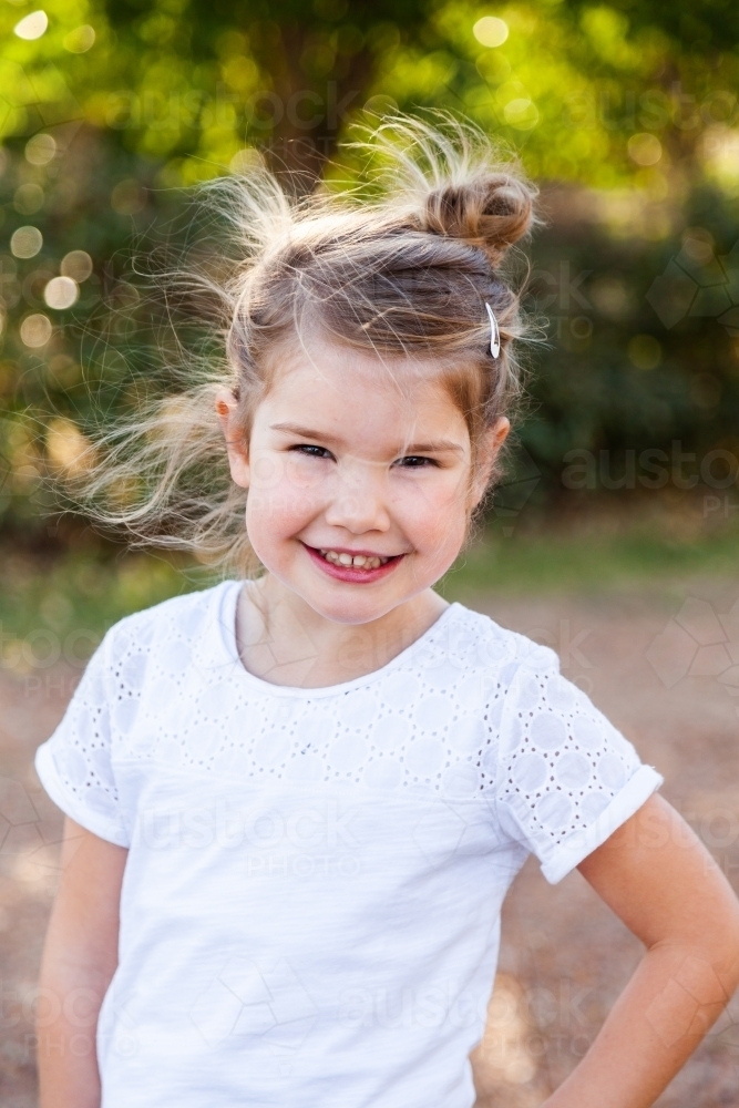 Portrait of a happy little girl with messy hair outside - Australian Stock Image