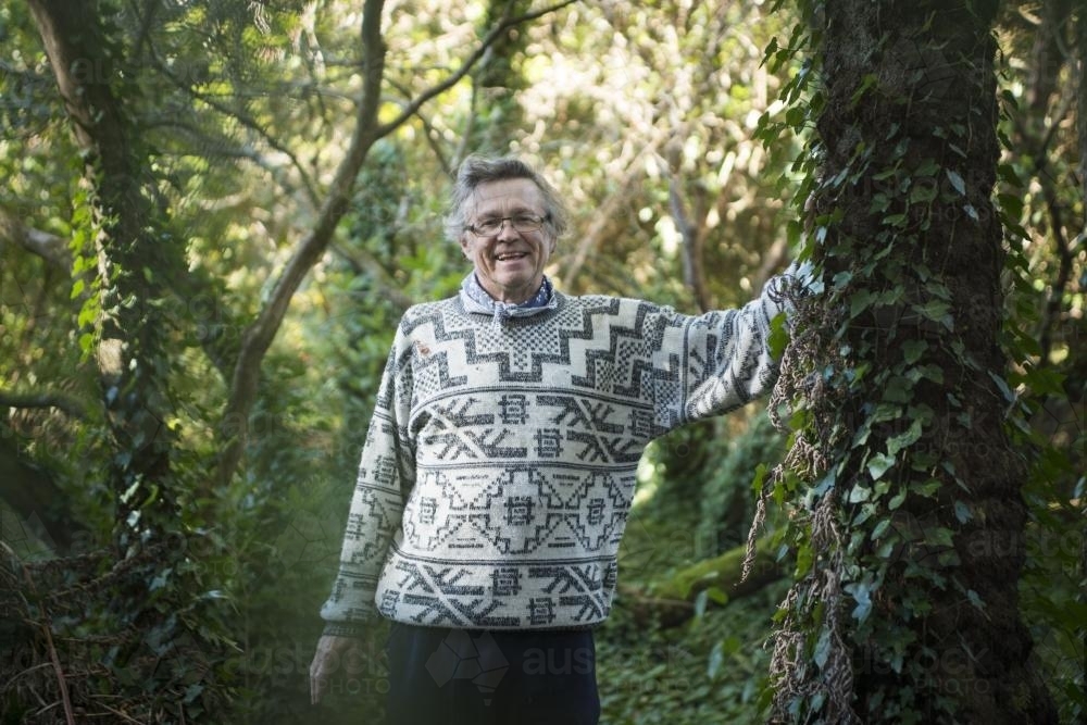 Portrait of a happy man with vine covered trees in forest - Australian Stock Image