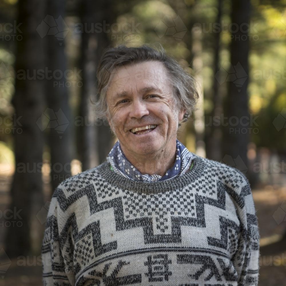 Portrait of a happy middle aged man among huge trees in the park - Australian Stock Image