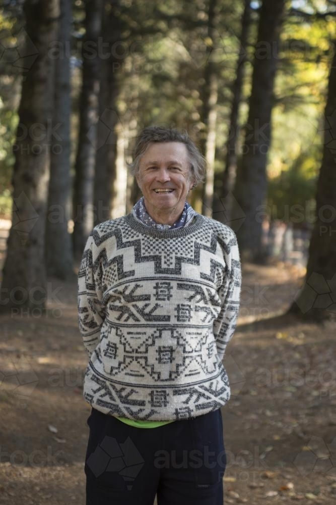 Portrait of a happy middle aged man among huge trees in the park - Australian Stock Image