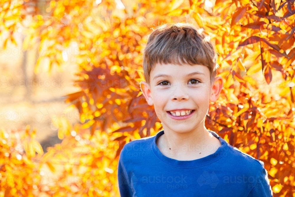 Portrait of a happy young boy laughing in autumn - Australian Stock Image