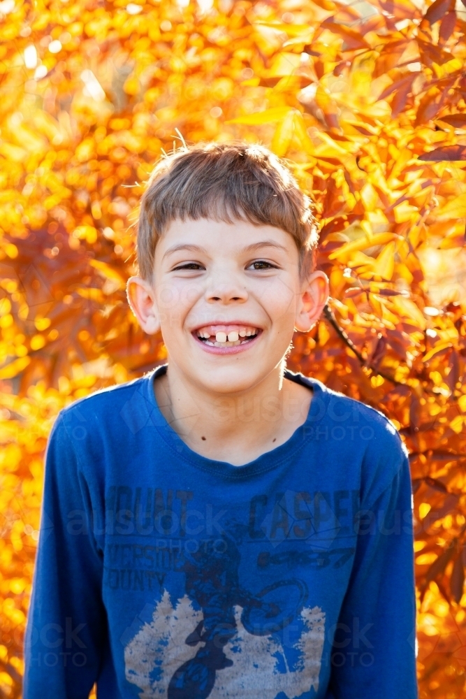 Portrait of a happy young boy laughing in autumn - Australian Stock Image