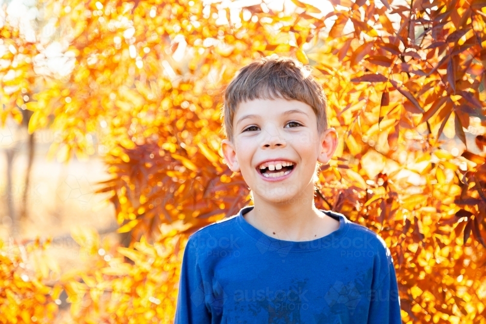 Portrait of a happy young boy laughing in autumn - Australian Stock Image