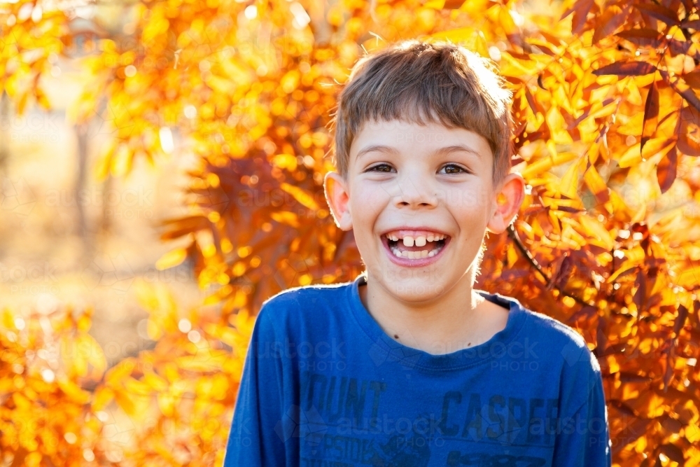 Portrait of a happy young boy laughing in autumn - Australian Stock Image