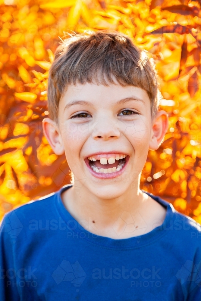 Portrait of a happy young boy laughing in autumn - Australian Stock Image