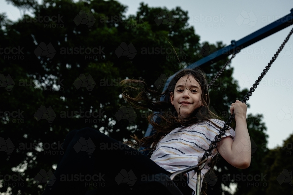 Image of Portrait of a happy, young girl on a playground swing at ...