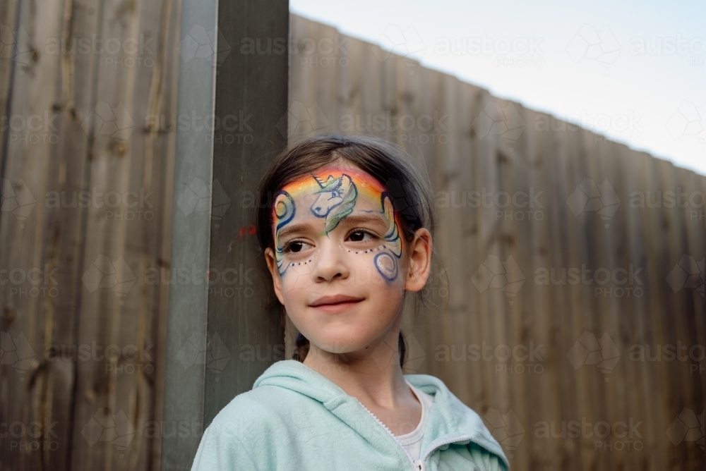 Portrait of a happy, young girl with unicorn face paint - Australian Stock Image