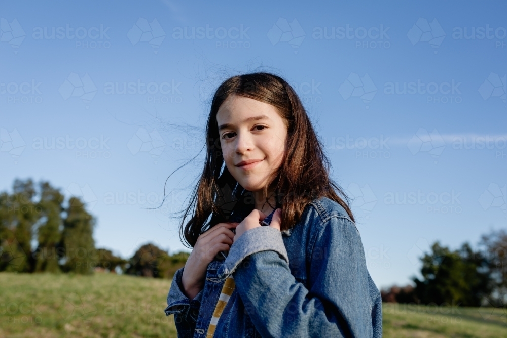 Portrait of a happy, young tween girl wearing a denim jacket - Australian Stock Image