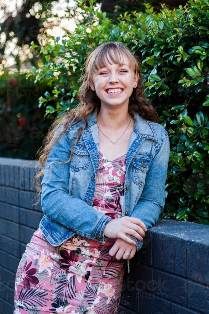 Portrait of a happy young woman leaning on a wall - Australian Stock Image