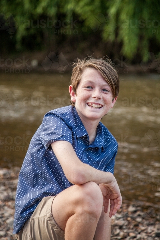 Portrait of a kid down on the stones by the river - Australian Stock Image