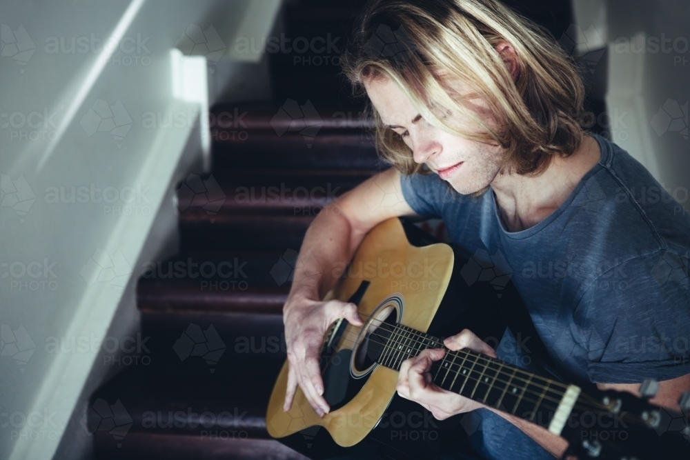 Portrait of a male musician playing guitar alone - Australian Stock Image