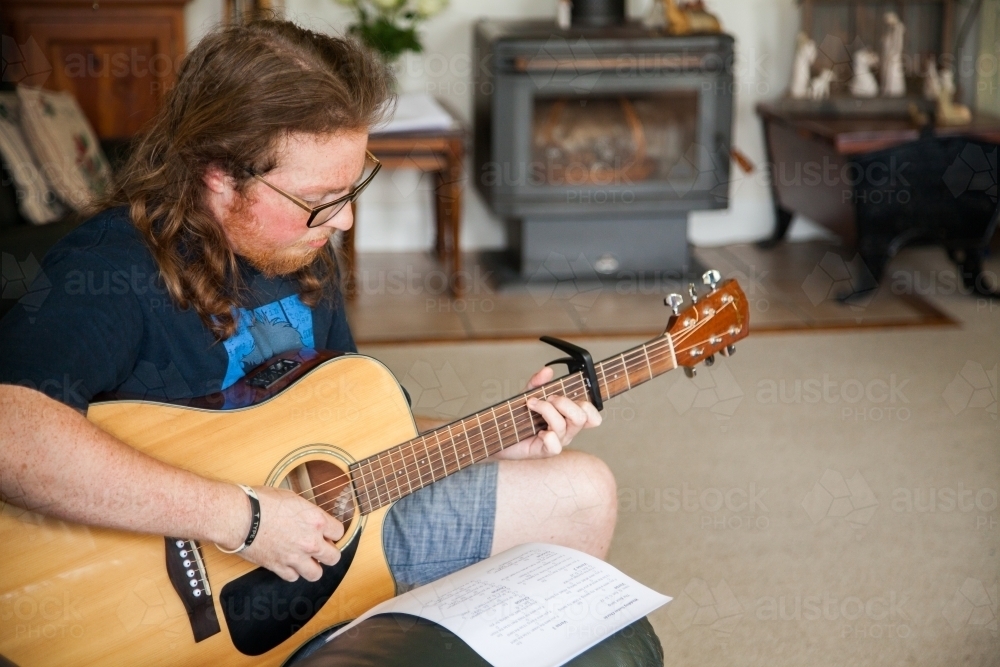 Portrait of a male musician playing guitar alone - Australian Stock Image