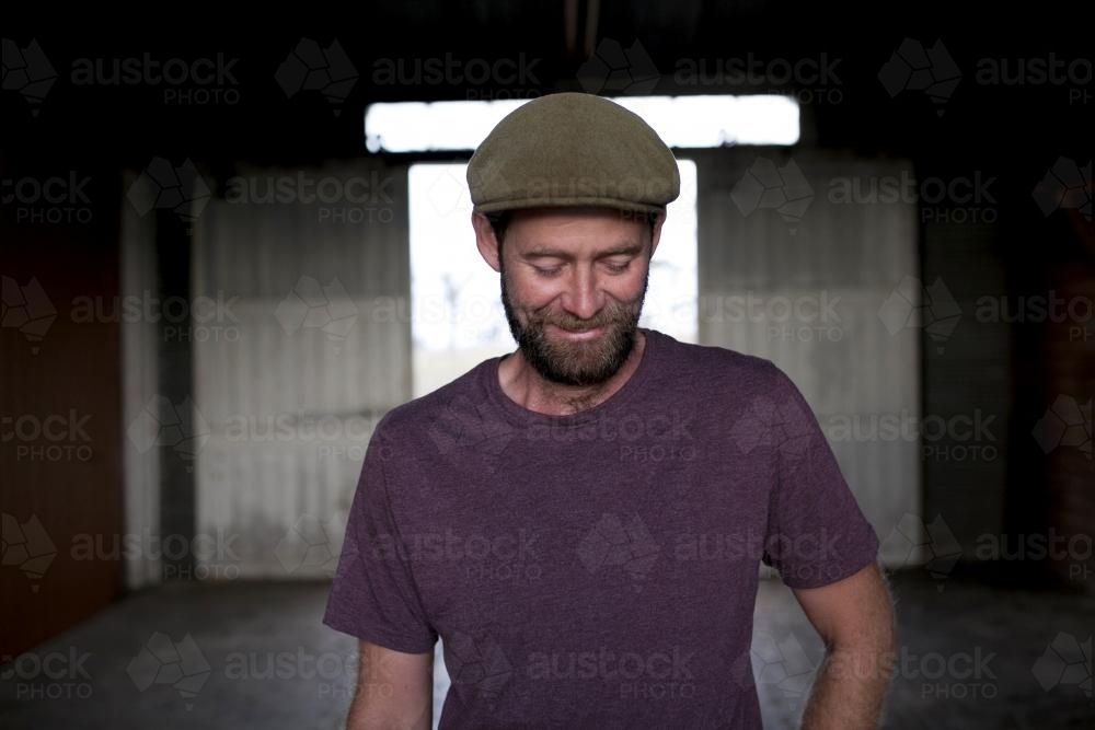 Portrait of a man wearing a hat with background of a dimly lit shed - Australian Stock Image